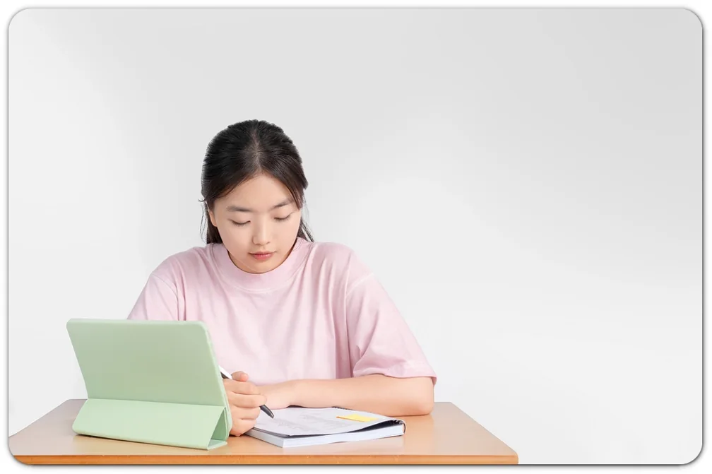 태블릿과 펼친 책을 보며 공부하는 학생