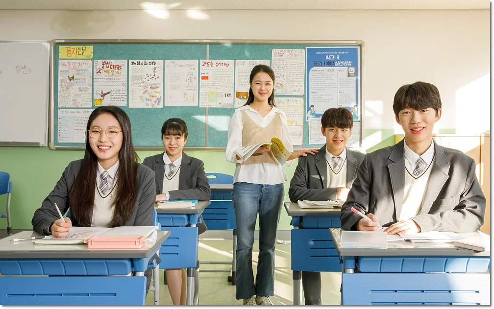 교실에서 교재를 펼친 학생들과 뒤에 서 있는 교사