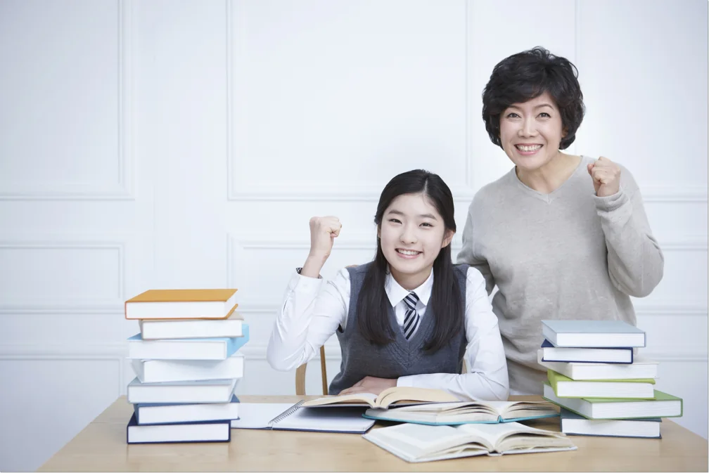 쌓인 책 옆에서 함께 앉은 학생과 어른
