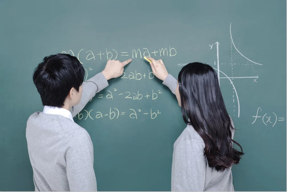 칠판에 적힌 식을 함께 살펴보는 학생들
