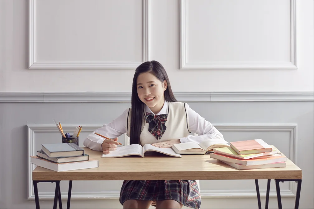 펼친 책에 글을 적는 학생