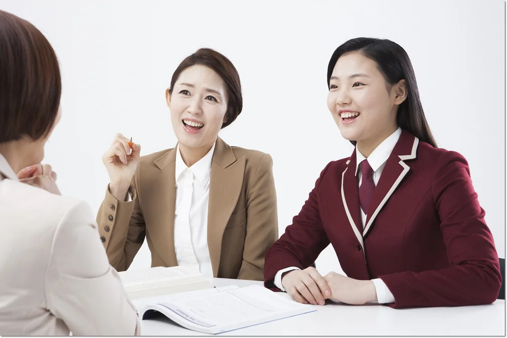 펼친 교재를 두고 대화하는 학생과 어른들
