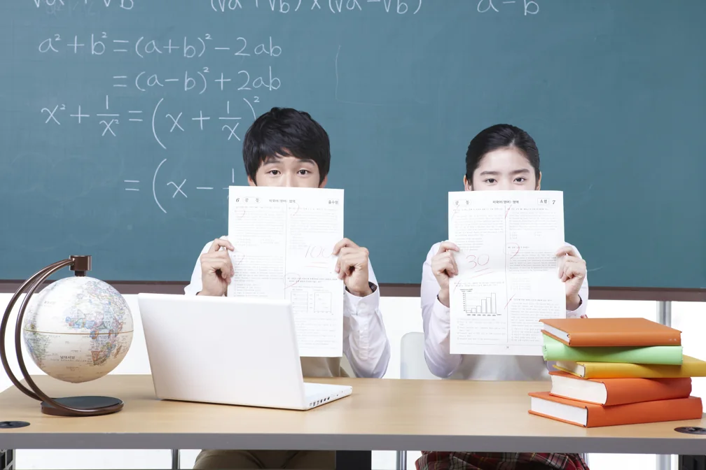 칠판 앞에서 각자 펼친 책을 들고 있는 두 학생