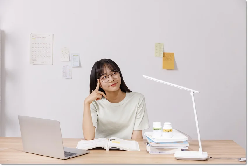 노트북과 책 옆에서 생각하는 학생