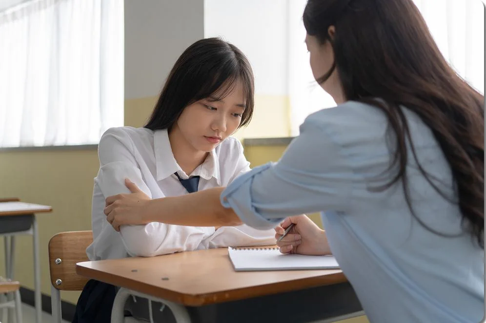 학생의 펼친 교재를 가리키는 교사